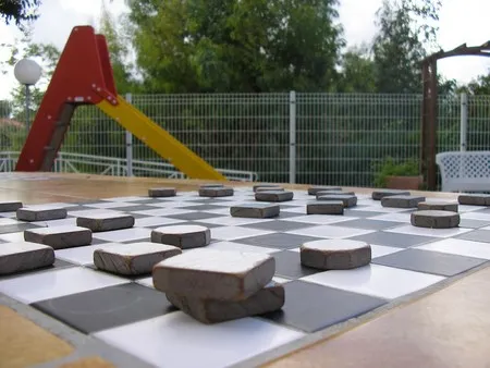 Détail d'un grand plateau de jeu de dames extérieur intégré à une table en pierre