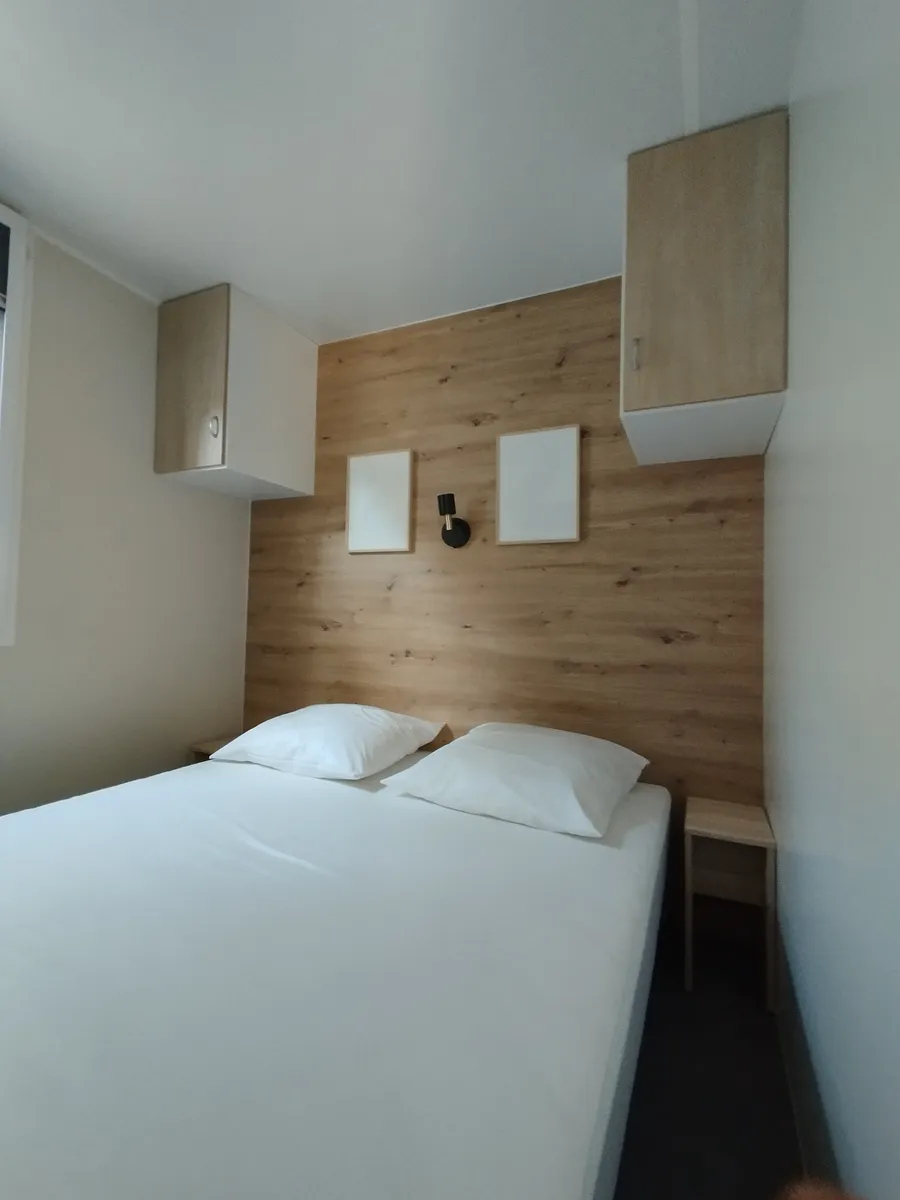Chambre double lumineuse de mobil-home avec rangements suspendus et mur effet bois