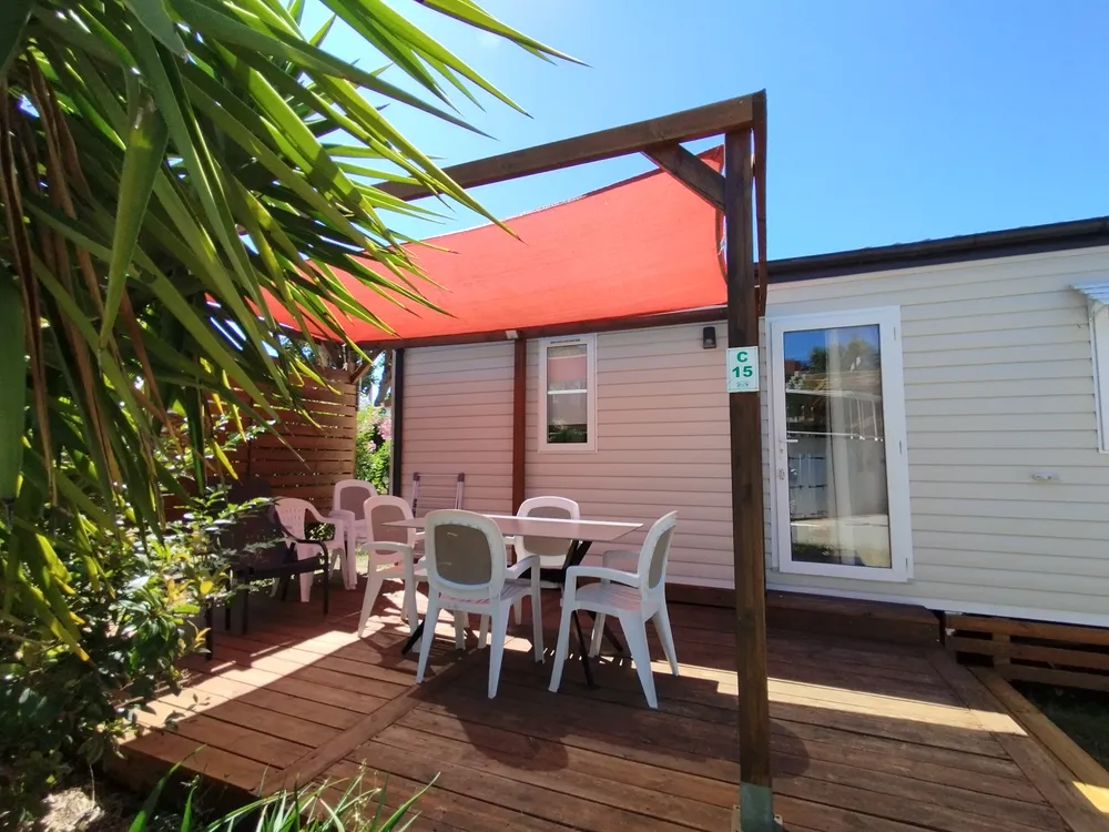 Mobile home terrace with garden furniture and red shade sail