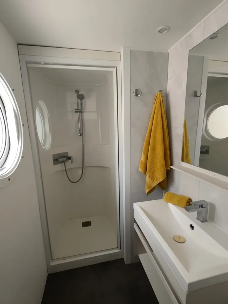 Coin lavabo avec miroir rond en bois et mur effet marbre dans un mobil-home