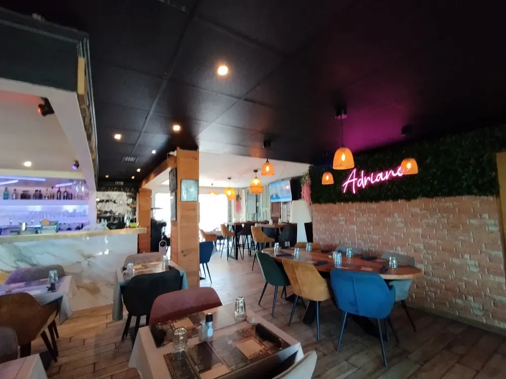 Espace d'un restaurant avec mur de briques, enseigne néon rose et grande table de groupe