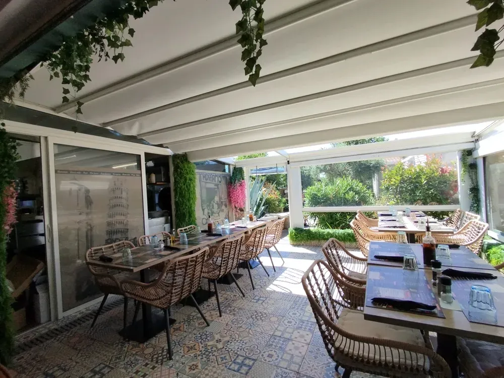 Terrasse ombragée de restaurant avec pergolas et mobilier en osier tressé